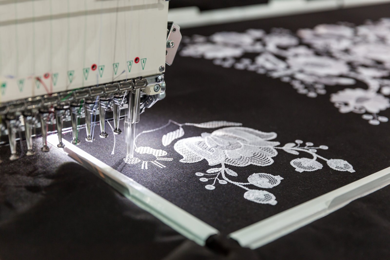 Modern embroidery machine stitching a custom crest design onto fabric.